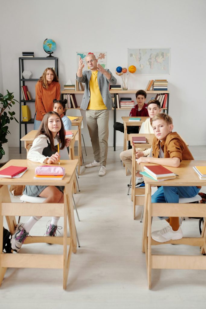 Teacher interacting with diverse group of students in modern classroom setting.